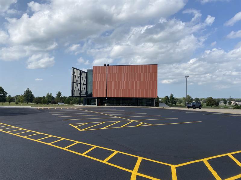 Newly painted crosswalk lines across a parking lot drive lane