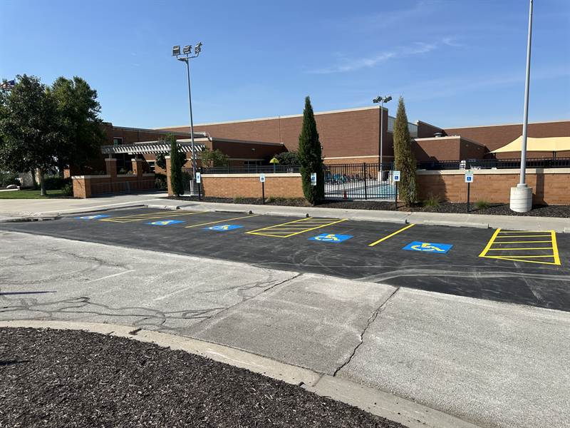 Custom stencils being painted onto fresh asphalt